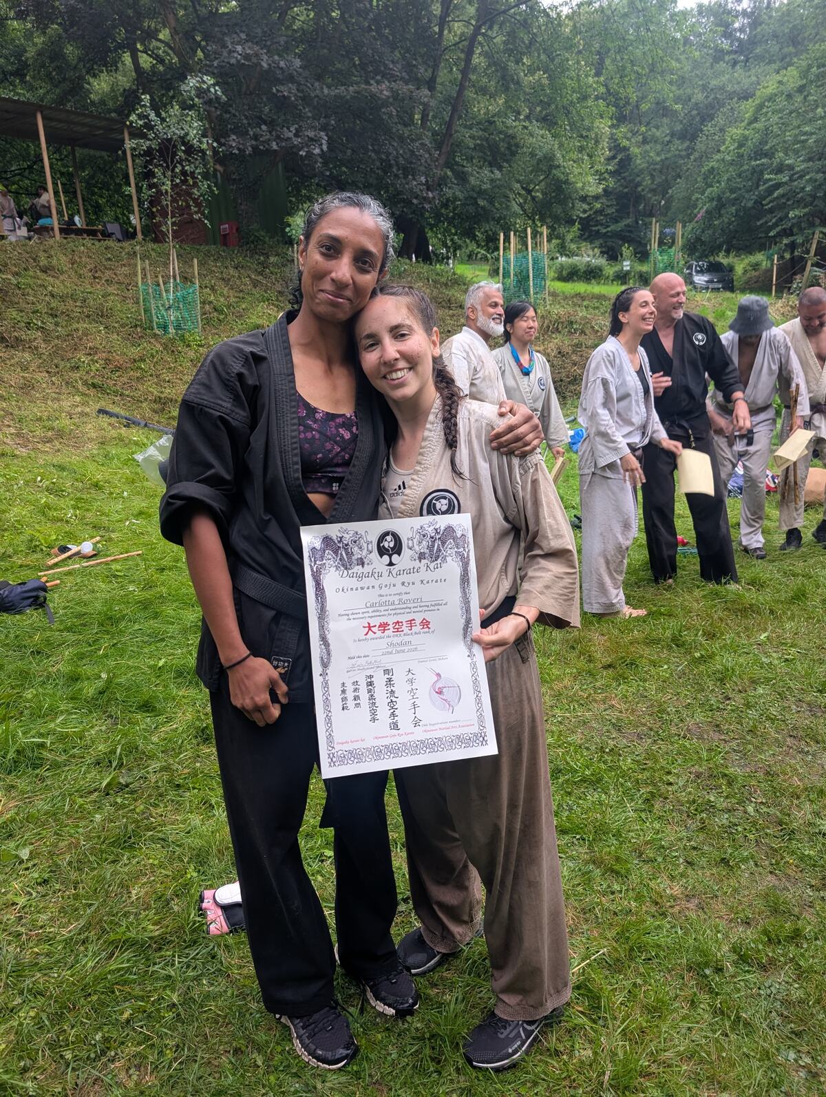 Two members at Summer Camp, one holding a newly awarded DKK dan grade certificate