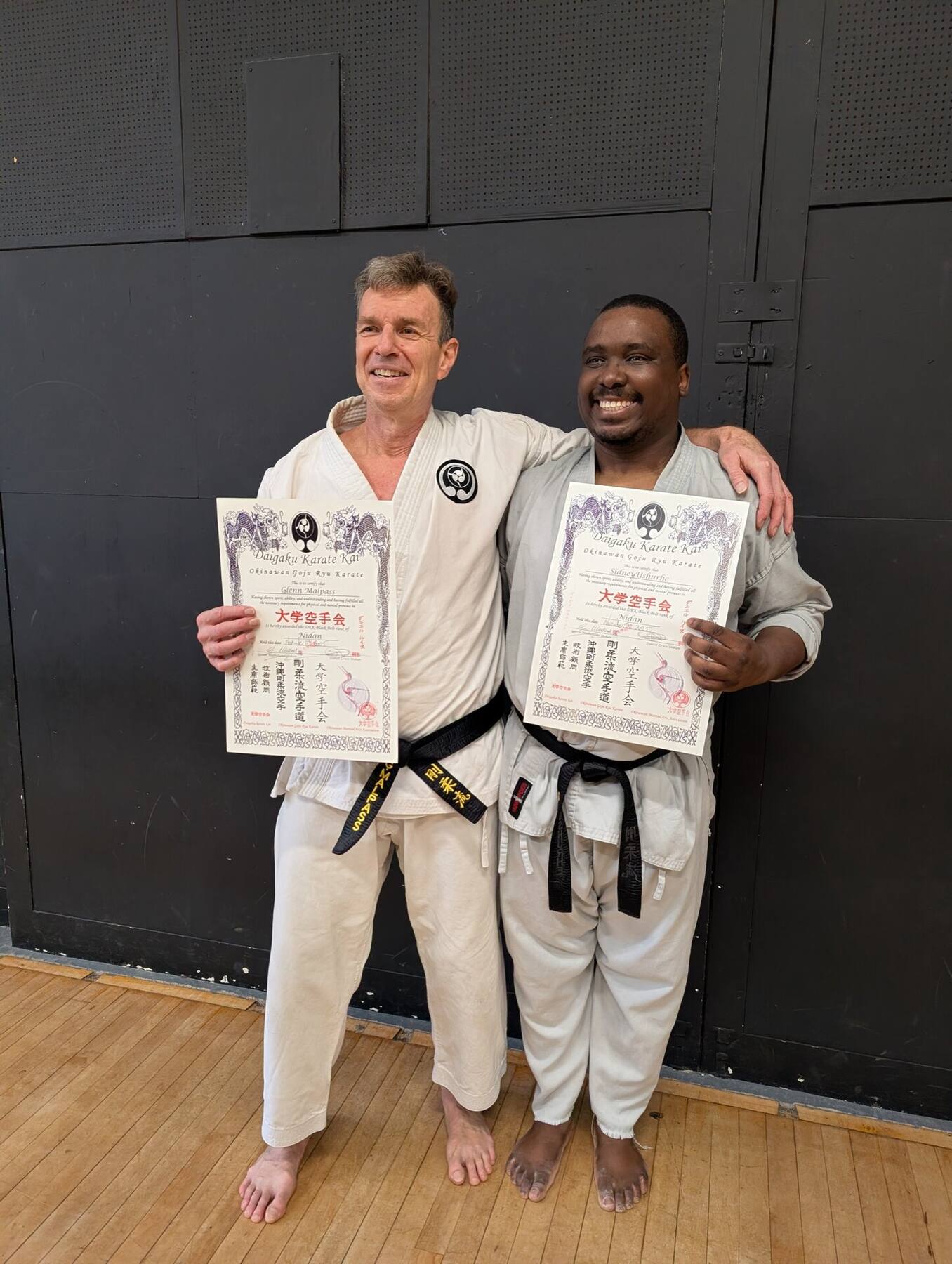 Two students with grading certificates