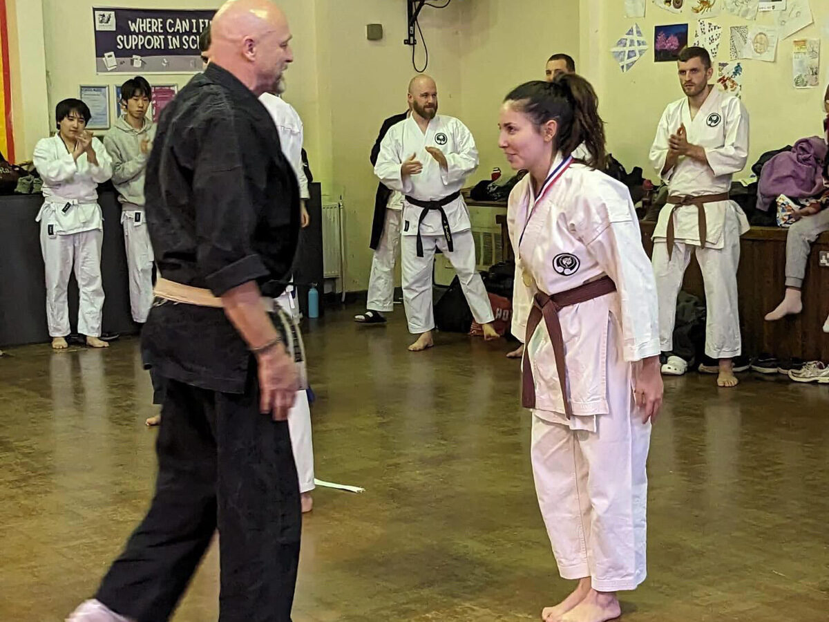 Carlotta wearing her medal after the kata tournament, the club applauding behind her