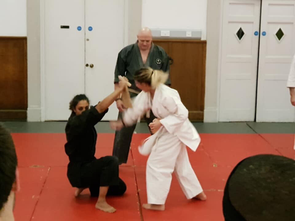 A board snapping in two during Carlotta's first tameshiwari, held by two club mates